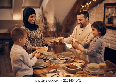 Happy Muslim parents and their kids sharing pita bread while eating dinner on Ramadan at home.  - Shutterstock ID 2131454041