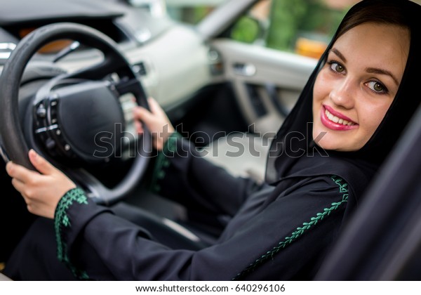 happy muslim woman driving\
car