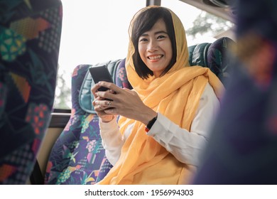 happy muslim woman using her mobile phone while riding a bus to go back home - Powered by Shutterstock