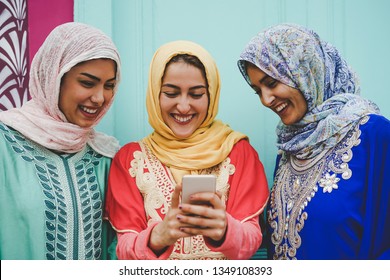 Happy Muslim Women Watching On Mobile Smart Phone In The College - Arabian Young Girls Having Fun With New Technologies Trends Apps - Millennials, Religion, Culture And Technology Concept