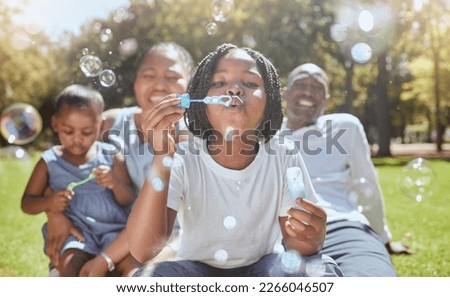 Happy, nature and black family blowing bubbles while playing, bonding and enjoying summer in the park. Happiness, father and mother with children having fun together in a green garden in South Africa