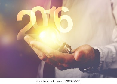 Happy new 2016 business year, businessman with light bulb and number 2016, retro toned image, selective focus.