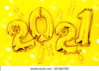 Happy New 2021 Year. Holiday Gold Metallic Balloon Numbers 2021 And Falling Serpentine On Yellow Background. Gold Foil Balloons Numeral 2021. Color Of The Year 2021, Illuminating