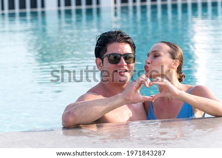 happy new wedding couple have enjoy and fun at swimming pool during honeymoon relaxing. Man and woman showheart shaped hand. in Love wedding vacation concept.