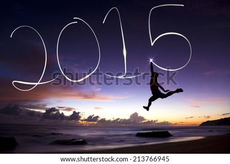 happy new year 2015.young man jumping and drawing 2015 by flashlight