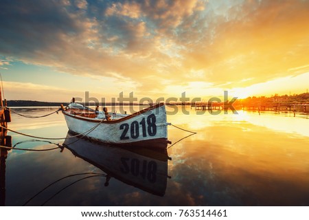 Happy New Year 2018 concept, lettering on the Boat with a reflection in the water at sunset