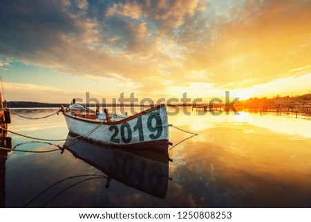 Happy New Year 2019 concept, lettering on the Boat with a reflection in the water at sunset