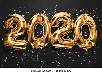 Happy New year 2020 celebration. Bright gold balloons figures, New Year Balloons with glitter stars on dark background. Christmas and new year celebration. Gold foil balloons 2020