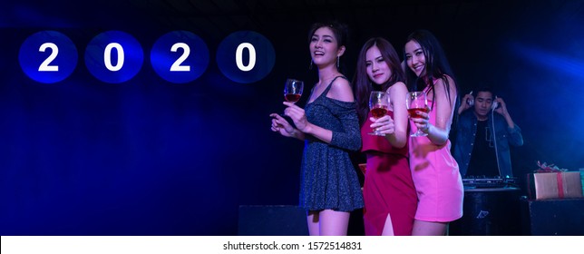 Happy New Year 2020 Celebrations Concept, Traveller People Holding Glasses Of Wine Together With Enjoying At Colourful Night Party Club.