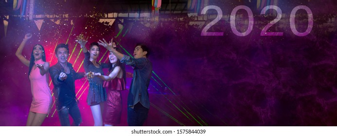 Happy New Year 2020 Celebrations Concept, Traveller People Holding Glasses Of Wine Together With Enjoying At Colourful Night Party Club.