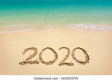 Happy New Year 2020, lettering on the beach with wave and clear blue sea. Numbers 2020 year on the sea shore, message handwritten in the golden sand on beautiful beach background. New Years concept. - Powered by Shutterstock