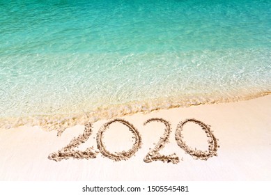 Happy New Year 2020, lettering on the beach with wave and clear blue sea. Numbers 2020 year on the sea shore, message handwritten in the white sand on beautiful beach background. New Years concept. - Powered by Shutterstock