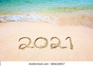 Happy New Year 2021, lettering on the beach with wave and clear blue sea. Numbers 2021 year on the sea shore, message handwritten in the golden sand on beautiful beach background. New Years concept. - Powered by Shutterstock