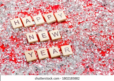 Happy New Year 2021. Wooden Letters With Silver Crystals And Confetti On A Red Background. Flat Lay.