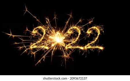 Happy New Year 2022. Creative numeral 2022 written sparkler fireworks. Beautiful Shiny sparkling art object isolated on black background for design