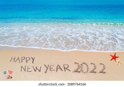 "happy new year 2022" written on a tropical beach