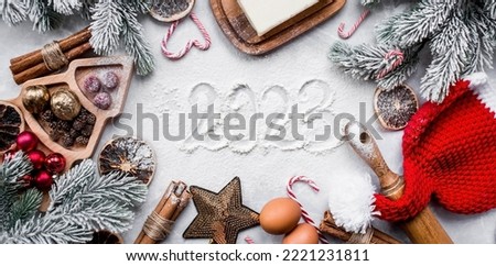 Happy New Year 2023. A frame of kitchen utensils, Christmas decorations, cinnamon, food and spruce branches on a marble background. A greeting card for Christmas. The concept of cafes and restaurants.