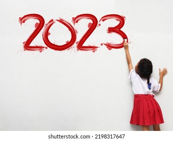 Happy new year 2023 Little girl holding a paint brush painting on a white wall background, Back to school idea concept - Shutterstock ID 2198317647