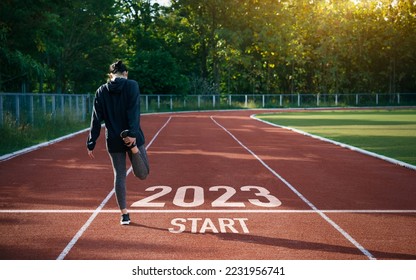 happy new year 2023 symbolizes the start of the new year. Rear view of a man preparing to run on the athletics track engraved with the year 2023. The goal of Success.Getting ready for the new year - Powered by Shutterstock