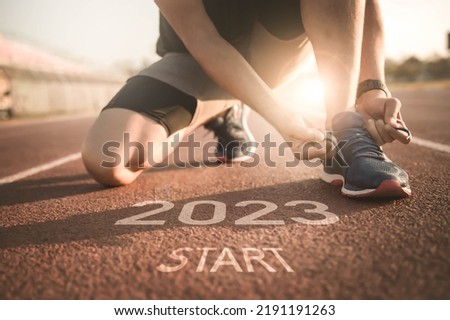 happy new year 2023,2023 symbolises the start into the new year.Start of people running on street,with sunset light.Goal of Success