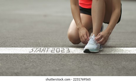 happy new year 2023,2023 symbolizes the start of the new year. Start with a woman preparing to run on the road engraved with the year 2023. The goal of Success. Getting ready for the new year - Powered by Shutterstock