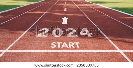 Happy New Year 2024 symbolizes the start of the new year. Rear view of a man preparing to run on the athletics track engraved with the year 2024. The goal of Success.Getting ready for the new yea
