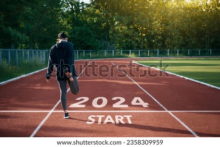 happy new year 2024 symbolizes the start of the new year. Rear view of a man preparing to run on the athletics track engraved with the year 2024. The goal of Success.Getting ready for the new year Foto stock © 