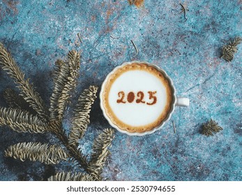 Happy New Year 2025 celebrated coffee cup with number 2025 over frothy surface flat lay on rustic blue background with dried pine branches. Holidays food art theme. (top view, space for text) - Powered by Shutterstock