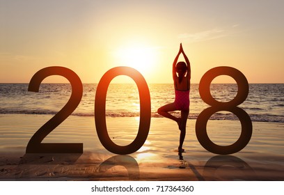 Happy new year card 2018. Silhouette of A girl doing Yoga vrikshasana tree pose on tropical beach with sunset sky background, watching the sunset, standing as a part of the Number 2018 sign. - Powered by Shutterstock