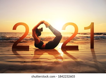 Gute neue Jahreskarte 2021. Silhouette von gesunden Mädchen mit Yoga Bow Pose auf tropischen Strand mit Sonnenuntergang Himmel Hintergrund, Frau, die Yoga als Teil der Nummer 2021 Zeichen.