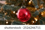 Happy New Year Christmas tree decorates with red glass ball on branch snow on background bokeh of side flickering light bulbs garlands for family winter holiday. Festival mood. Noel