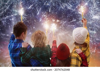 Happy new year. Family watching fireworks. Parents and kids celebrate new 2022 year. Winter holiday party. Outdoor fun. Children, mother and father with sparkler watch firework show.