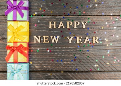 Happy New Year Festive Background. Gift Boxes And Wooden Text. Multicolored Stars Confeti