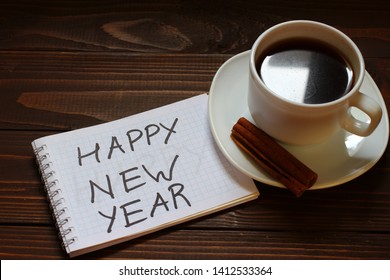 Happy New Year inscription and word in a notebook near a cup of coffee