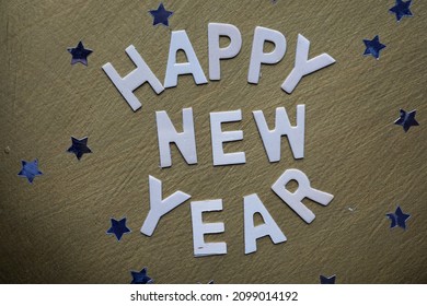 Happy new year written on a golden table next to stars                     