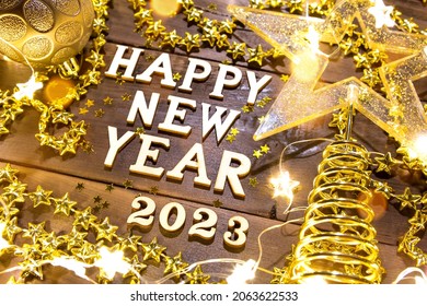 Happy New Year-wooden letters and the numbers 2023 on a festive background with sequins, stars, glitter, lights of garlands. Greetings, postcard. Calendar, cover