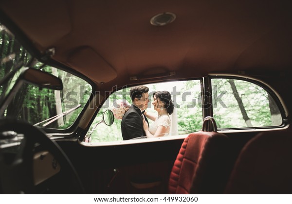 Happy newlywed couple, man and wife kissing near\
stylish retro car
