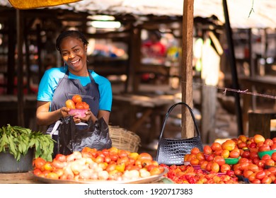 Happy Nigerian Trader In A Local Market Holding A Bowl Of Tomatoes