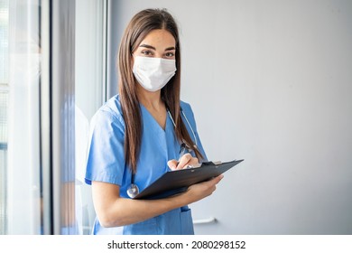 Happy Nurse Working At The Hospital. Portrait Of A Happy Latin American Nurse Working At The Hospital And Looking At The Camera Smiling. Nurse With N95 Face Mask Going Through Medical Reports 