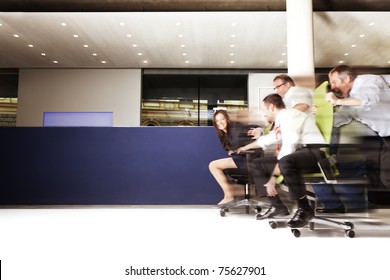 Happy Office Staff Competing In An Chair Race And Having A Lot Of Fun, Blue Copy Space Area.