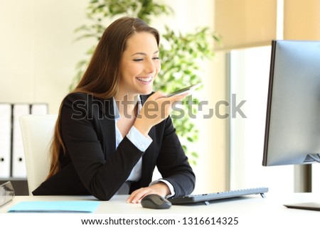 Happy office worker working using smart phone voice recognition to send message