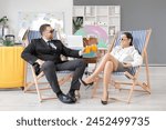 Happy office workers in sunglasses sitting on deckchairs and drinking cocktails in office. Summer vacation concept