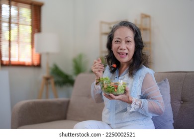 Happy old asian woman eating fresh green salad. Senior woman good healthy at home. Exercise and healthy diet concept - Powered by Shutterstock