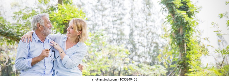 Happy Old Caucasian Couple Smiling In Park On Sunny Day, Hoot Senior Couple Relax In The Forest Spring Summer Time. Healthcare Lifestyle Retirement Grandparents On Vacation Concept Panoramic Banner