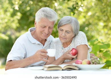 Happy old couple with drink and book - Powered by Shutterstock