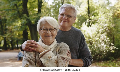 Happy Old Couple Hugging In Park. Senior Man Flirting With Elderly Woman. Autumn Day. High Quality Photo