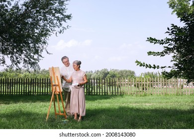 Happy old couple painting in the park high quality photo