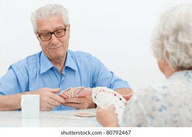 Happy Old Couple Playing Together With  Cards At Home