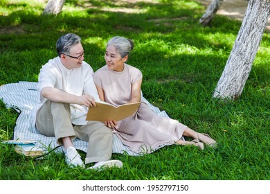 Happy old couple sitting on the park grass reading smiling - Powered by Shutterstock