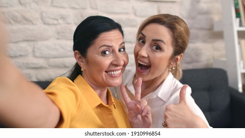 Happy Old Lady And Her Daughter Are Taking Selfie While Holding A Mobile Phone. Young Woman Doing Thumbs Up (all Is Well) Sign. 